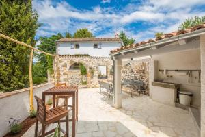a patio with a table and chairs and a house at Holiday Home Jela in Dobrinj