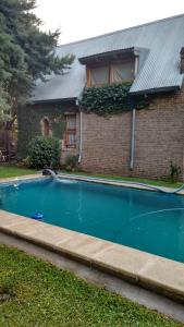 una piscina frente a una casa de ladrillo en La casa de Hostal del Sol en Rosario