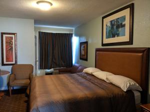 a hotel room with a bed and a chair at San Marina Motel Daytona in Daytona Beach