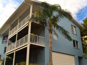 a blue house with a palm tree in front of it at Beaches 1 -LJHooker yamba in Yamba