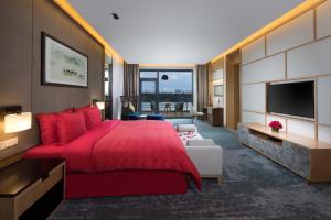 ein Hotelzimmer mit einem roten Bett und einem TV in der Unterkunft Holiday Inn Kunshan Huaqiao, an IHG Hotel in Kunshan