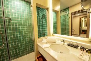 a green tiled bathroom with a sink and a shower at Garden Sentral Hotel in Kuala Belait