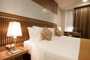 a bedroom with a large white bed with a lamp at Garden Sentral Hotel in Kuala Belait