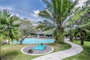 a swimming pool in a yard with palm trees at Maya Villa - Seminyak in Seminyak