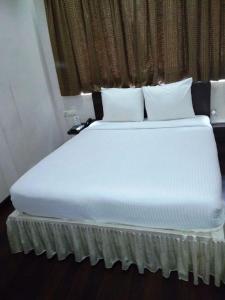 a bed with white sheets and pillows in a room at Hotel Lee International in Kolkata