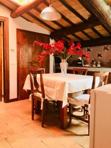 een eettafel met een vaas met rode bloemen erop bij Sotto i tetti del borgo in Spoleto