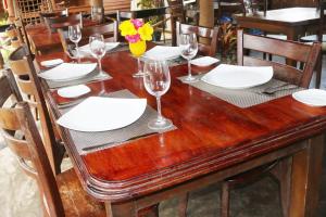 a wooden table with white plates and wine glasses at Scoop Cabana Kitesurfing in Kalpitiya