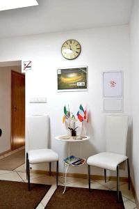 dwa krzesła i stół i zegar na ścianie w obiekcie Hostel Gdańsk Sun and Sea w Gdańsku
