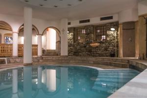 einen Pool in einem Hotel mit Säulen und einer Steinmauer in der Unterkunft Alphotel Stocker Alpine Wellnesshotel in Sand in Taufers