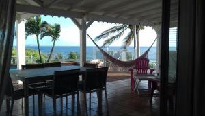 a porch with a hammock and a table and chairs at Villa Vue Océan in Le Moule