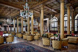Le hall de l'hôtel est doté de tables, de chaises et d'un lustre. dans l'établissement Hotel Danieli, Venice, à Venise