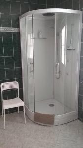 y baño con ducha y silla junto a una silla. en Hotel Le Café, en Pohořelice