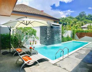 a swimming pool with an umbrella and a table and chairs at Coco Kamala: Breathtaking villa in Kamala Beach
