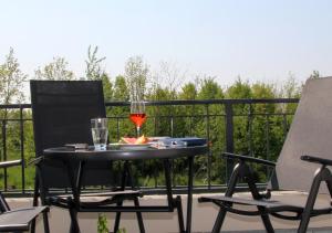 a table with a glass of wine and two chairs at Ferienhaus Bellevue in Fehmarn