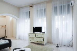 ein Wohnzimmer mit einem TV auf einer Kommode mit Fenstern in der Unterkunft MainStreet apartman in Subotica
