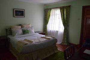 a bedroom with a large bed and a window at Adies Garden Suites in Nairobi