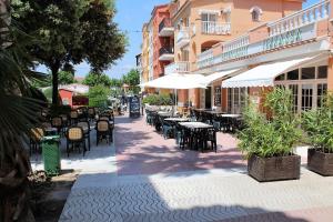 an outdoor patio with tables and chairs and umbrellas at Marina Beach Hollidays Mimosa in Empuriabrava