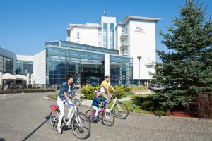 three people riding bikes in front of a building at Ikar Plaza in Kołobrzeg