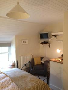 a bedroom with a bed and a chair and a tv at Ty Capel in Machynlleth