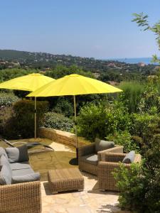 a patio with umbrellas and couches and chairs at Villa les Coralines in Les Issambres