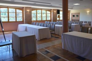 a room with white tables and chairs and windows at Jardines de La Santa in Totana