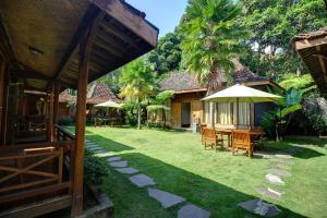 een achtertuin met een tafel en stoelen en een parasol bij Cempaka Villa in Borobudur