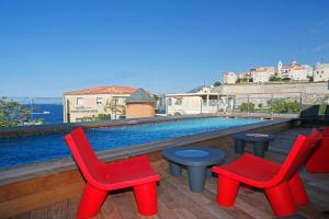 a deck with red chairs and a swimming pool at Hôtel Méditerranée in Calvi