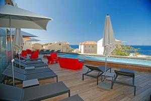 a swimming pool with chairs and umbrellas on a deck at Hôtel Méditerranée in Calvi