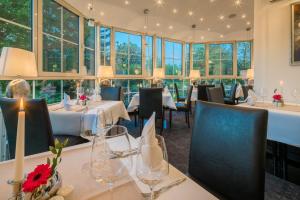 een restaurant met tafels, stoelen en ramen bij Best Western Hotel Windorf in Leipzig
