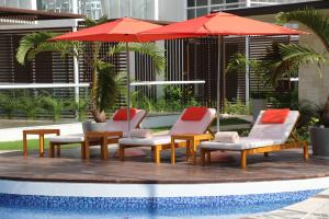 a group of chairs and an umbrella next to a pool at Terrazas Apartments by Bahia Principe in Tulum