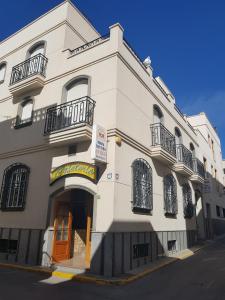 un edificio blanco con puerta de color naranja y balcón en Hostal San Andres en Carboneras