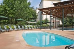 - une piscine avec des chaises longues et des parasols dans l'établissement Domaine des Bains, à Vals-les-Bains