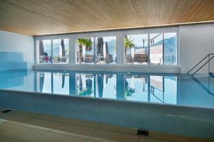 a swimming pool in a building with a reflection in the water at Alpenblick Weggis - Panorama & Alpen Chic Hotel in Weggis