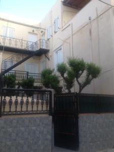 a building with a black fence and two trees at Soulas apart -Ρέα- in Ano Syros