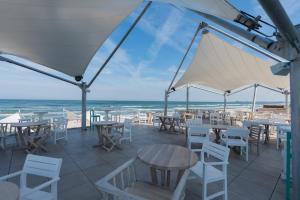 a patio with tables and chairs and the ocean at White Tower Mamaia in Mamaia