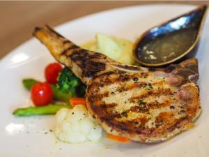 a plate of food with a piece of meat and vegetables at Solitaire Bangkok Sukhumvit 11 in Bangkok