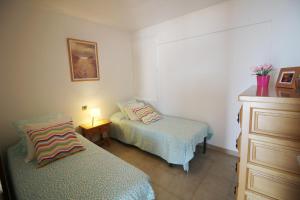 エンプリアブラバにあるBasic Comfort Apartment Karina 16º 0102のベッドルーム1室(ベッド2台、ランプ付きドレッサー付)