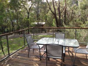 a patio with a table and chairs on a deck at Wattletree Cottage in Halls Gap