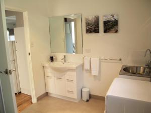 a white bathroom with a sink and a mirror at Wattletree Cottage in Halls Gap +12 photos
