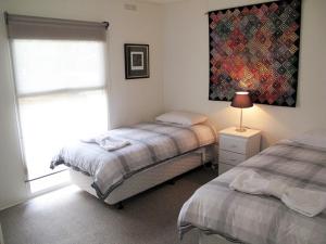 a bedroom with two beds and a lamp and a window at Wattletree Cottage in Halls Gap