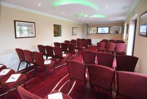 a conference room with red chairs and tables at Spanhoe Lodge in Harringworth