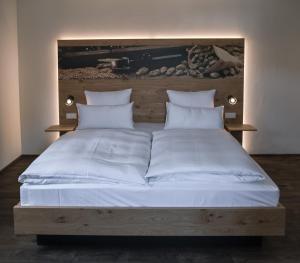 a large bed with white sheets and pillows at Bierhotel - Hotel & Brauereigasthof Schneider in Essing