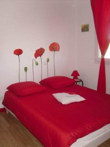 a bedroom with a red bed with red pillows at Gîte Bien Etre in Boulogne-sur-Gesse