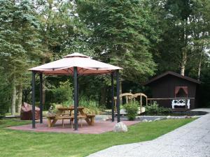 uma mesa de piquenique e um guarda-chuva ao lado de um parque infantil em Nordsee Domizil Schobüll em Husum