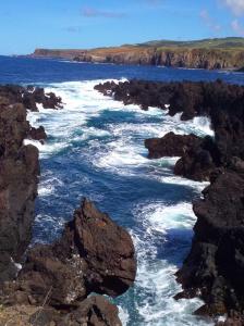 a large body of water with rocks and the ocean at Casa do ti' Marrão in Praia da Vitória