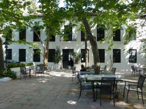 um pátio com mesas e cadeiras em frente a um edifício branco em Hotel del Balneario em Tolox