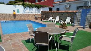 a patio with a table and chairs next to a pool at Hostal Mini Golf in Los Caños de Meca