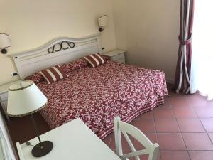 1 dormitorio con 1 cama y 1 mesa con lámpara en Villa Rosella Resort en Roseto degli Abruzzi