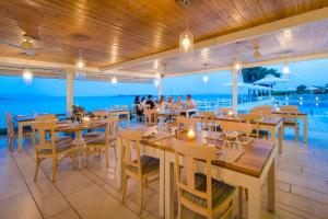a restaurant with tables and chairs and a view of the ocean at Saint George Hotel in Chrissi Akti