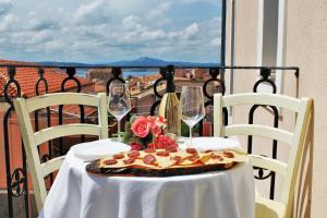 a table with a pizza and wine glasses on a balcony at AHR Leonis Residence La Maddalena in La Maddalena